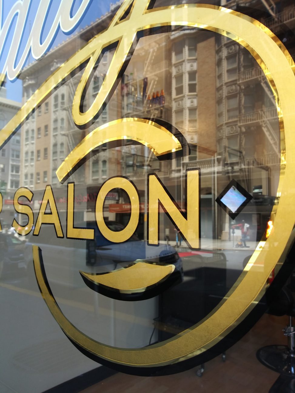 photo of a gold leaf sign on a window, text reads "Salon"